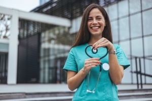 Joyful nurse forming a heart with her stethoscope