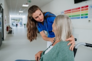 Young medical professional speaking with a senior patient in a wheelchair